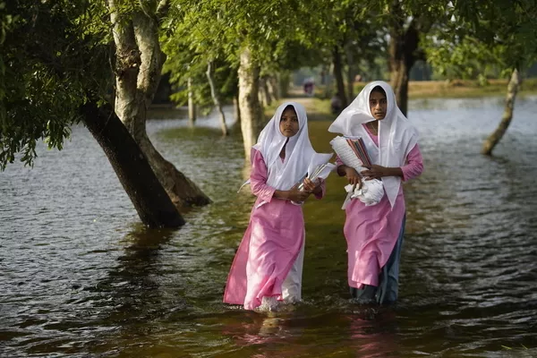 Bangladesh. Girls wade through floodwaters on the way to school in Sunamganj, Bangladesh.